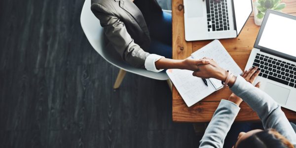 High angle shot of two businesswomen shaking hands in an office